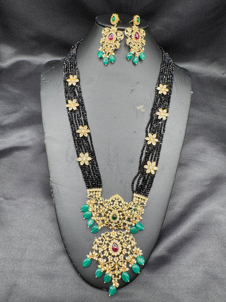 A bunch of black beads with an uncut stone pendant with matching earrings