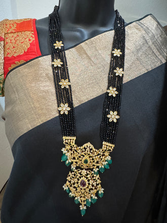 A bunch of black beads with an uncut stone pendant with matching earrings