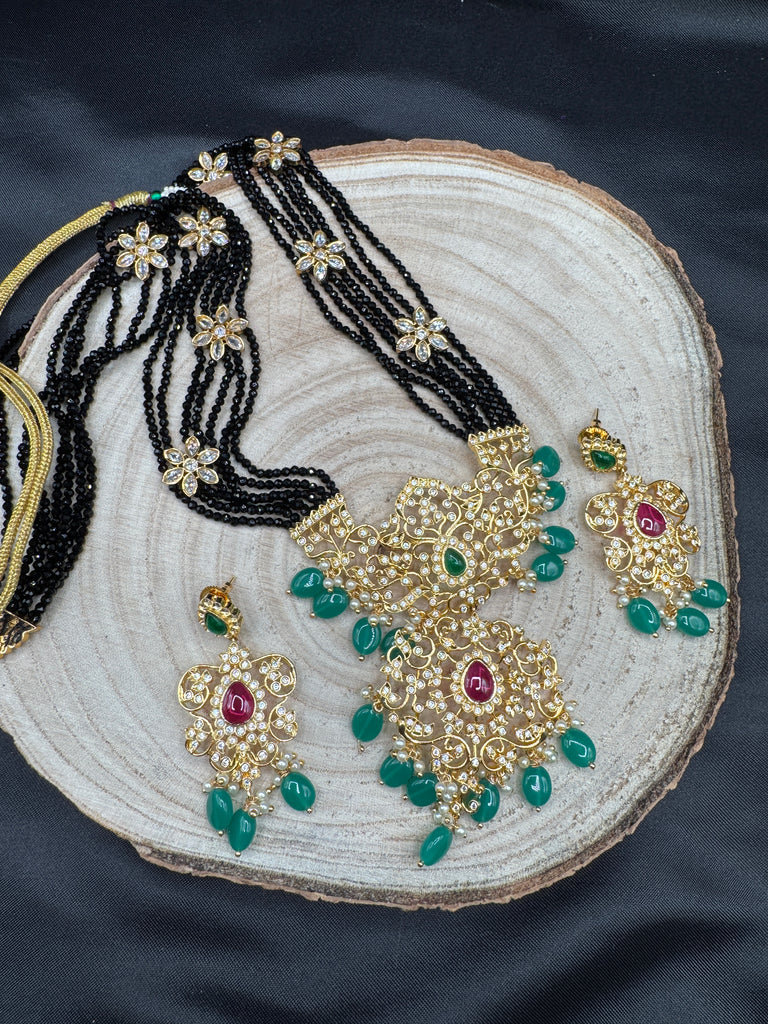 A bunch of black beads with an uncut stone pendant with matching earrings