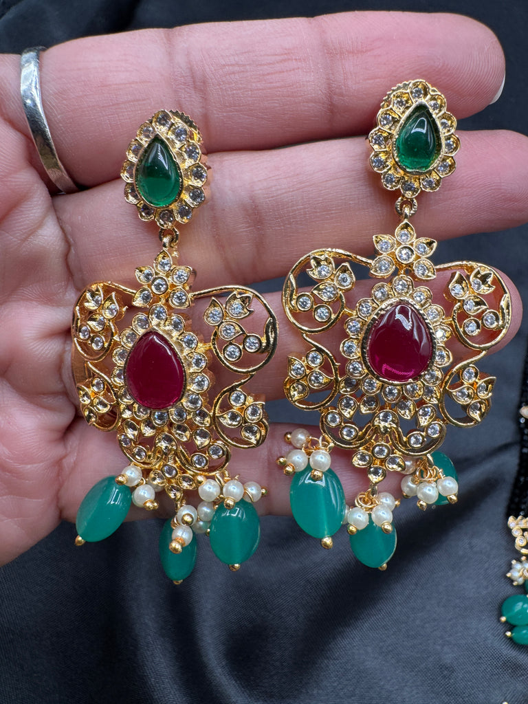 A bunch of black beads with an uncut stone pendant with matching earrings