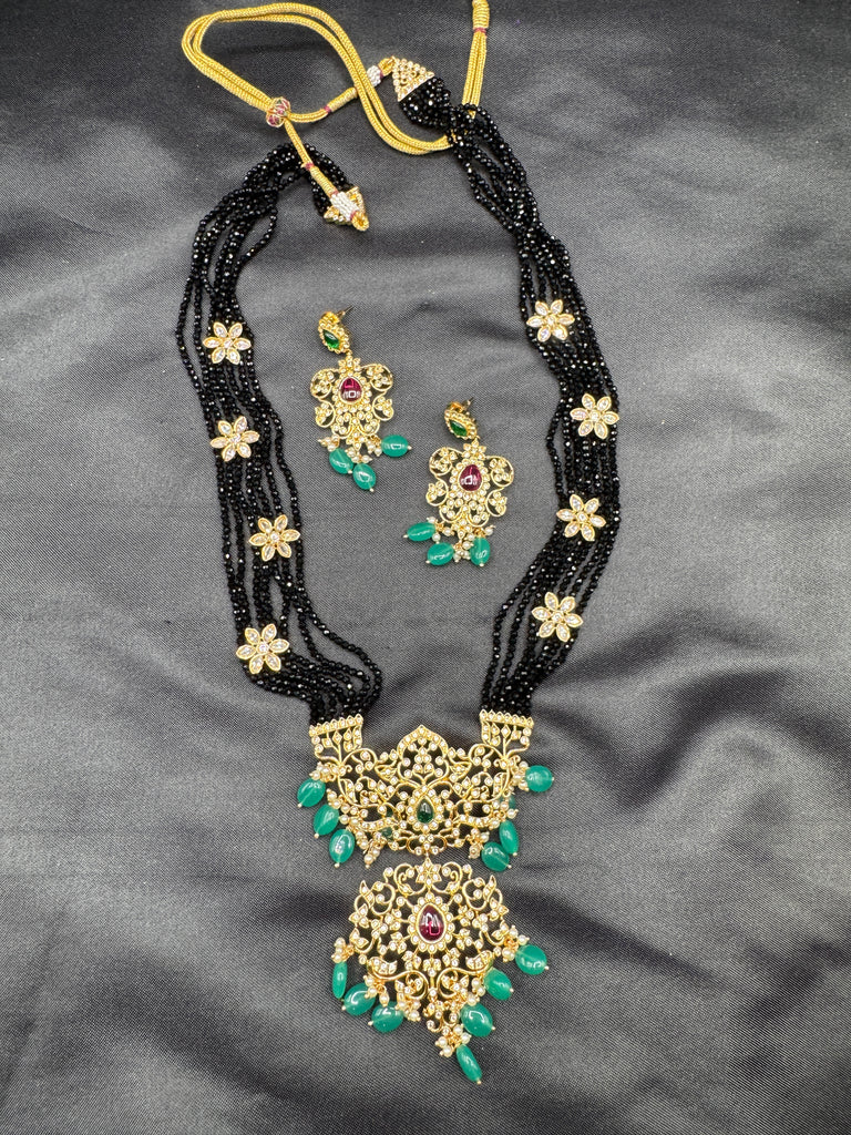 A bunch of black beads with an uncut stone pendant with matching earrings