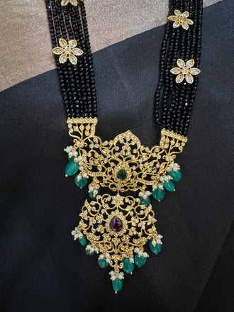 A bunch of black beads with an uncut stone pendant with matching earrings