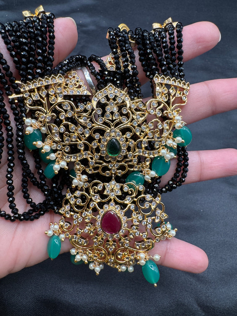 A bunch of black beads with an uncut stone pendant with matching earrings