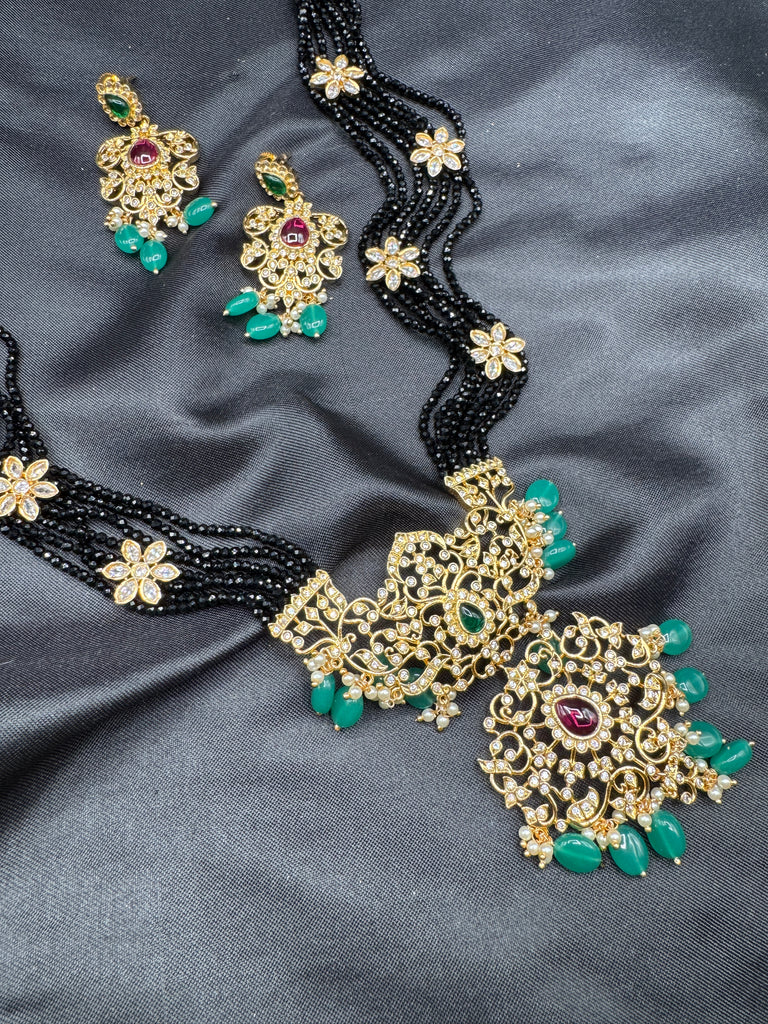 A bunch of black beads with an uncut stone pendant with matching earrings